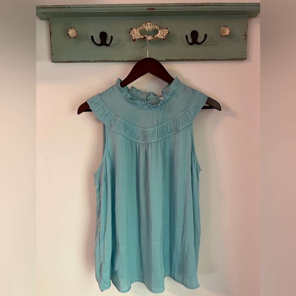 Ruffle neck sleeveless shell; satin feel.